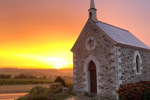 Chapelle au coucher de soleil avec ciel orangé.